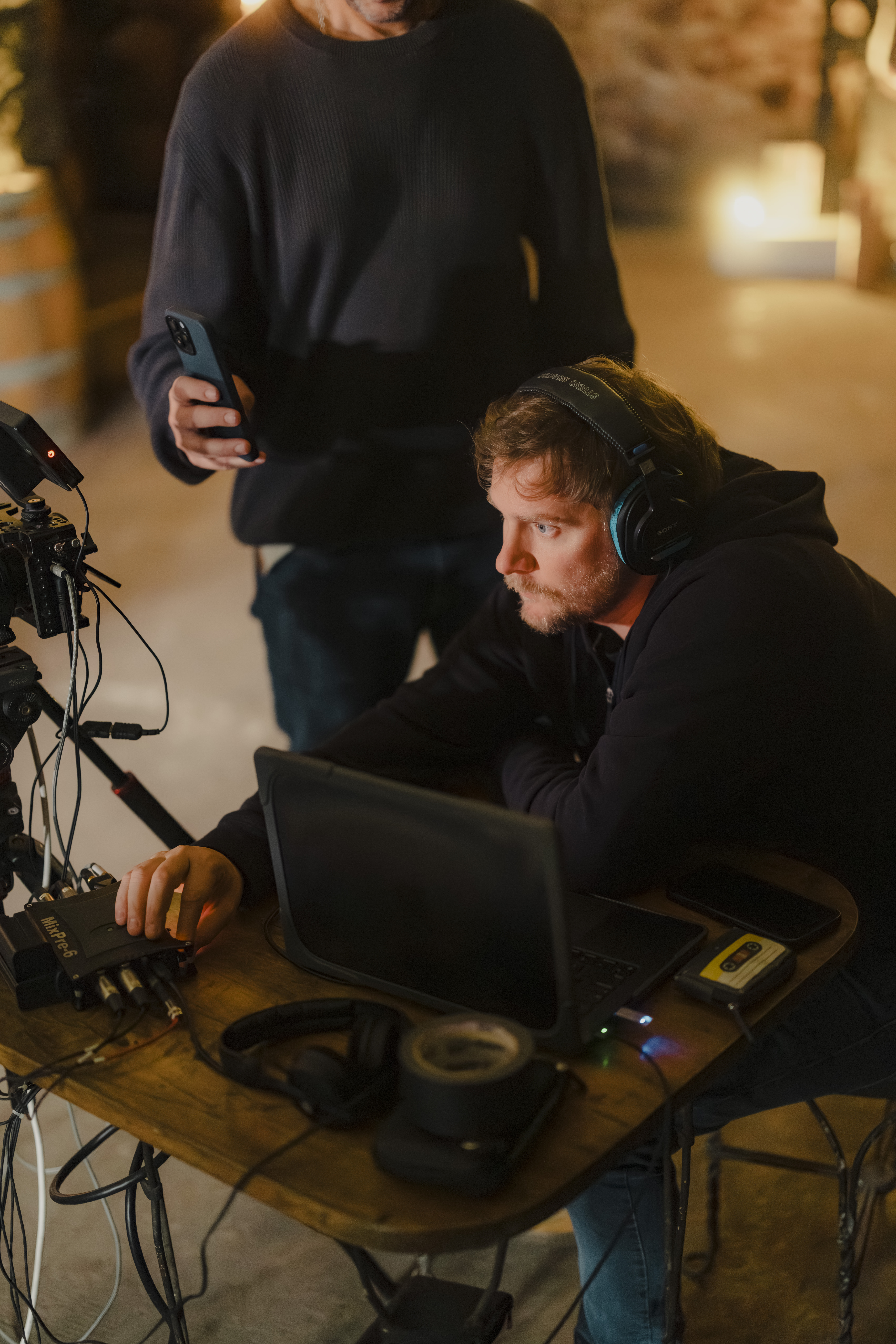 Operador de cámara con auriculares mirando el monitor junto a otra persona